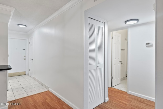 corridor with light wood-type flooring and crown molding