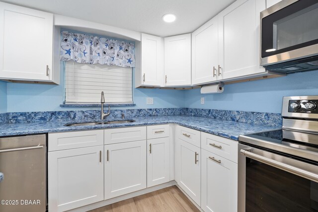 3807 S Atlantic Ave Unit 203, Daytona Beach, FL 32118 - kitchen featuring stainless steel appliances, a sink, white cabinets, light wood-style floors, and recessed lighting