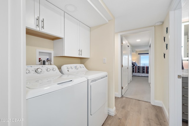 3807 S Atlantic Ave Unit 203, Daytona Beach, FL 32118 - laundry area with cabinet space, washing machine and clothes dryer, light wood finished floors, and baseboards