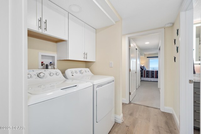 3807 S Atlantic Ave Unit 203, Daytona Beach, FL 32118 - laundry area with cabinet space, washer and dryer, light wood finished floors, and baseboards