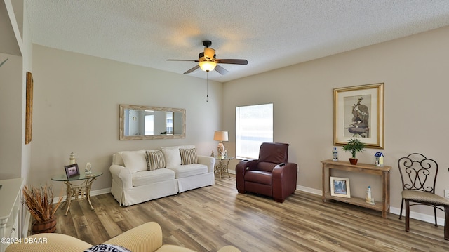 living room with ceiling fan, wood-type flooring, and a textured ceiling