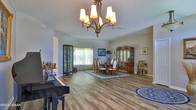 interior space featuring a textured ceiling, hardwood / wood-style flooring, and an inviting chandelier