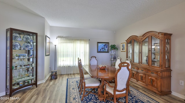 dining area with wood-type flooring and a textured ceiling