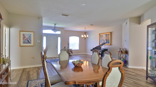 dining room featuring hardwood / wood-style floors, a chandelier, and a textured ceiling