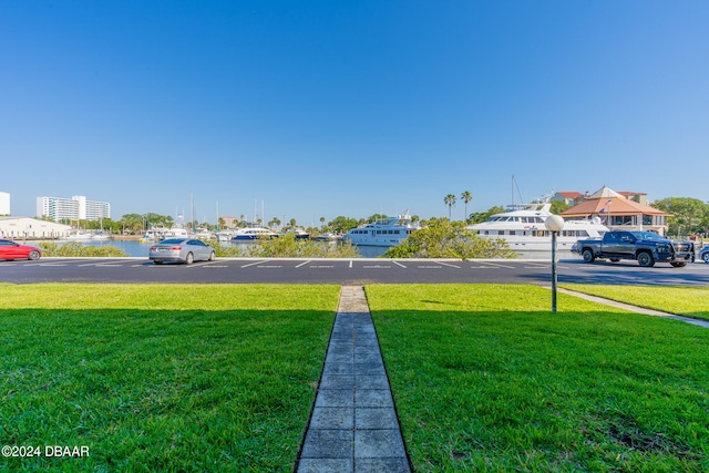 view of parking with a water view and a lawn