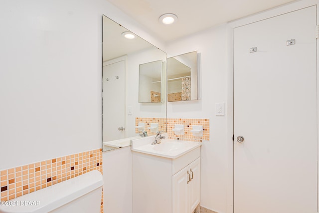 bathroom with toilet, vanity, and decorative backsplash