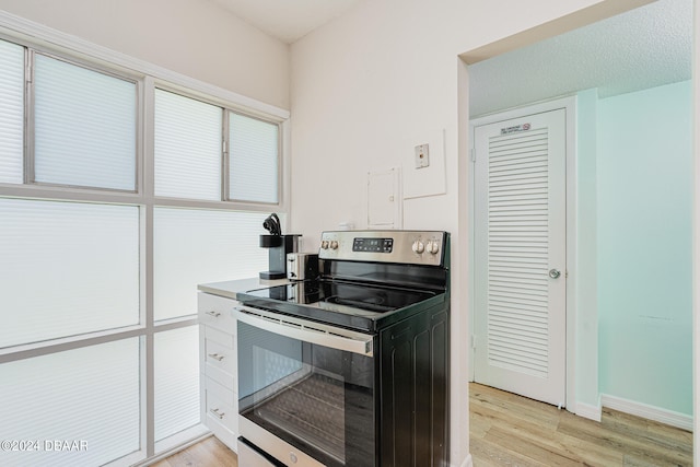 kitchen featuring white cabinets, light hardwood / wood-style floors, a textured ceiling, and stainless steel range with electric cooktop