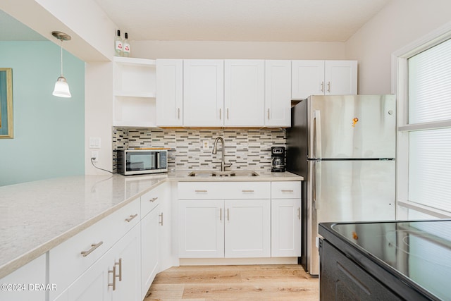 kitchen with white cabinets, light wood-type flooring, appliances with stainless steel finishes, and sink