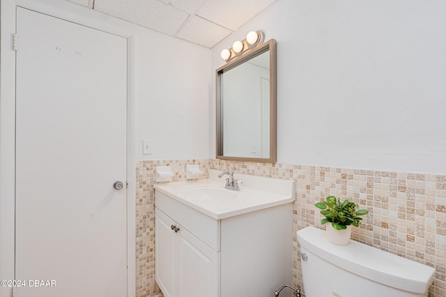 bathroom with vanity, toilet, tile walls, and a drop ceiling