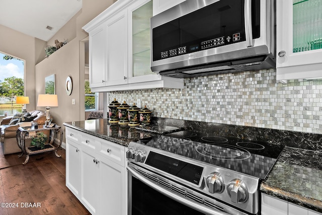 kitchen with stainless steel appliances, white cabinetry, dark hardwood / wood-style floors, and dark stone countertops