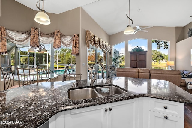 kitchen featuring dark stone countertops, ceiling fan, sink, and vaulted ceiling