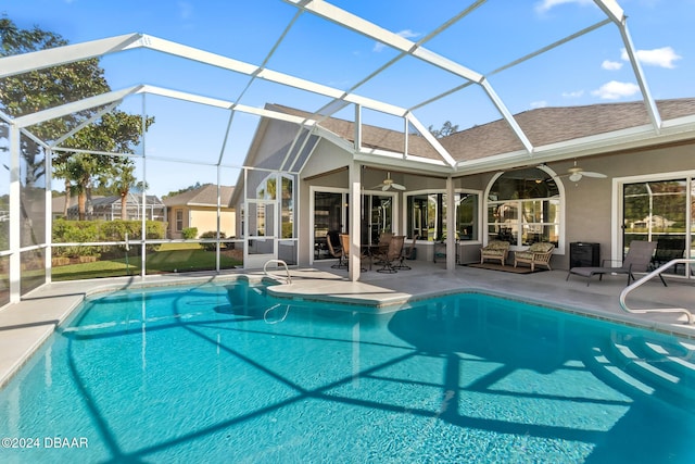 view of pool featuring a patio, glass enclosure, and ceiling fan