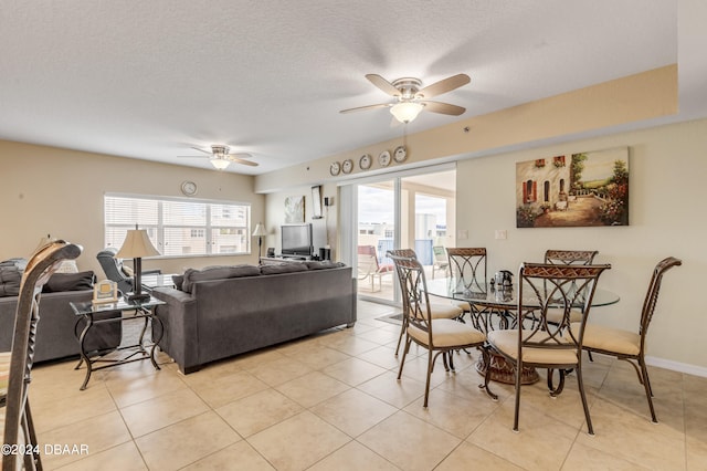 tiled dining space with a textured ceiling and ceiling fan