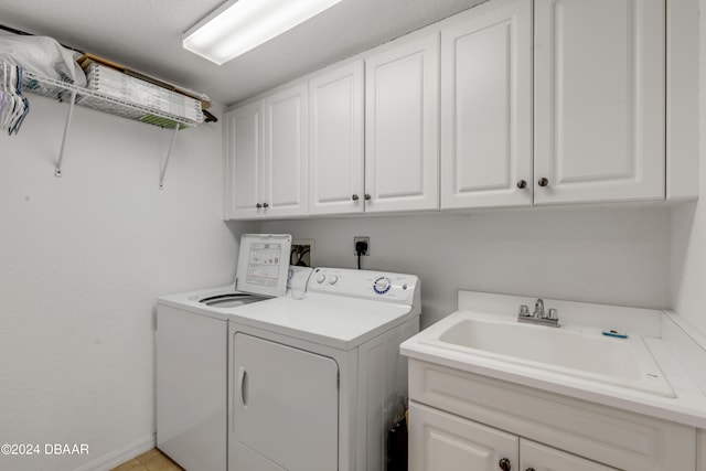 washroom with cabinets, sink, and washing machine and clothes dryer