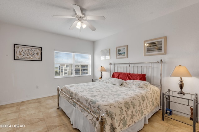 bedroom featuring a textured ceiling, light tile patterned floors, and ceiling fan