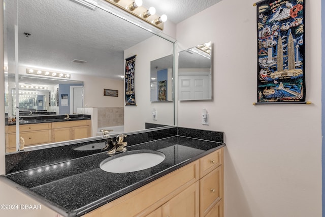 bathroom featuring vanity, a bathing tub, and a textured ceiling