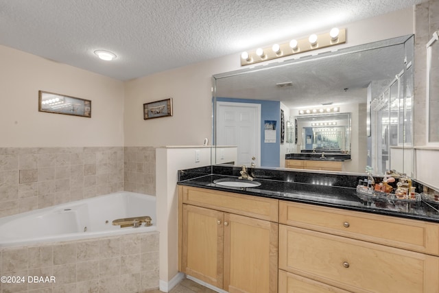 bathroom featuring vanity, a textured ceiling, and tiled tub