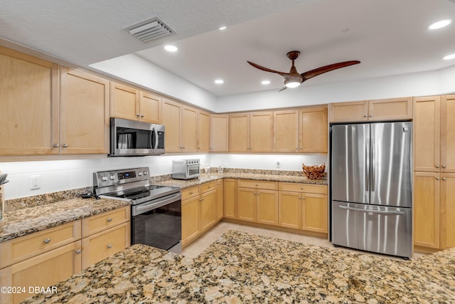 kitchen featuring stainless steel appliances, light brown cabinets, and light stone counters