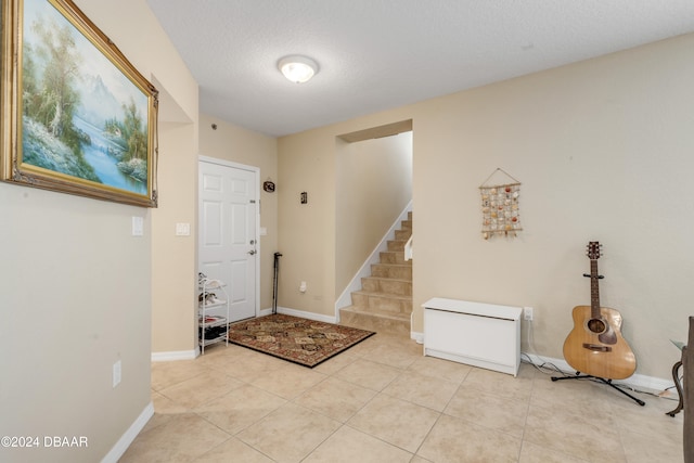 entryway with a textured ceiling and light tile patterned floors