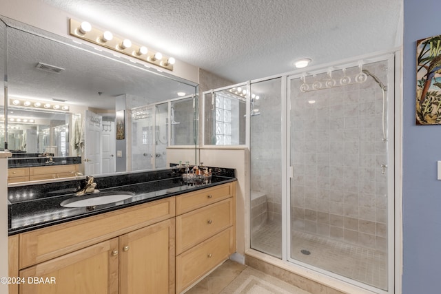 bathroom with vanity, a textured ceiling, tile patterned floors, and a shower with door