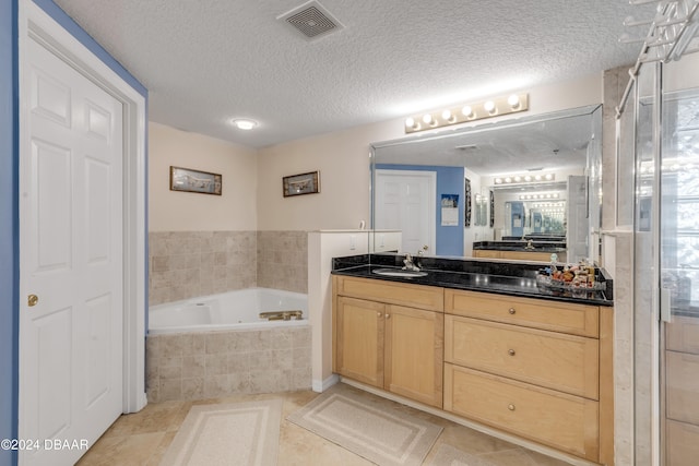 bathroom featuring shower with separate bathtub, vanity, a textured ceiling, and tile patterned floors