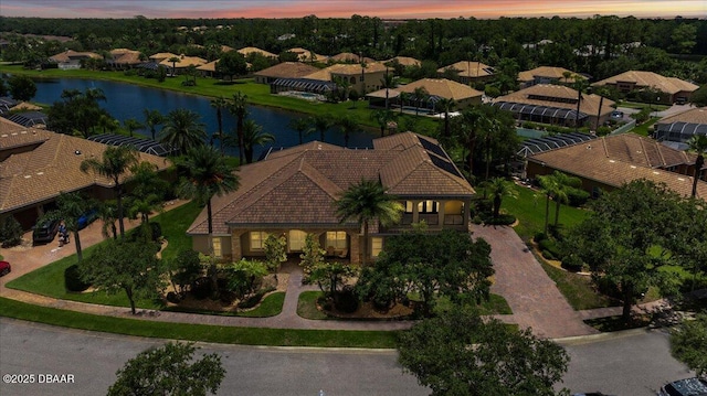 aerial view at dusk featuring a water view and a residential view