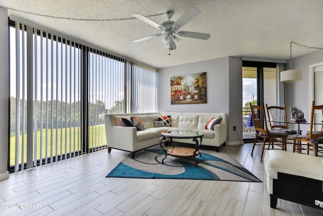 living room featuring light hardwood / wood-style floors, a textured ceiling, and ceiling fan