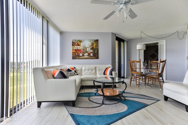 living room featuring light wood-type flooring, a textured ceiling, and ceiling fan