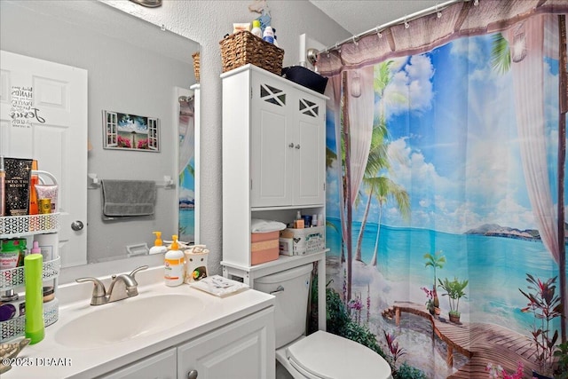 bathroom with a textured wall, curtained shower, vanity, and toilet