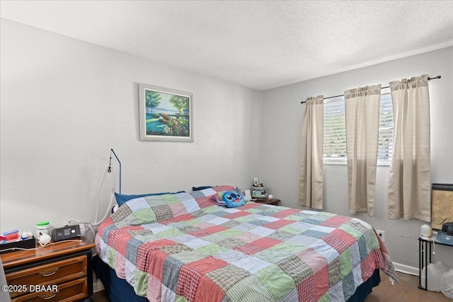 bedroom with a textured ceiling and wood finished floors