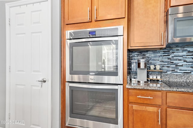 kitchen featuring stone counters, tasteful backsplash, appliances with stainless steel finishes, and brown cabinetry