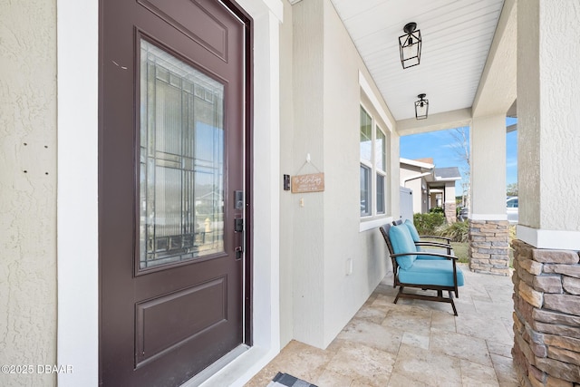 entrance to property featuring a porch and stucco siding