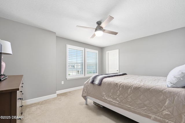 bedroom featuring a ceiling fan, light carpet, a textured ceiling, and baseboards