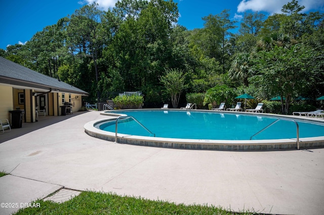 pool with a patio area and fence