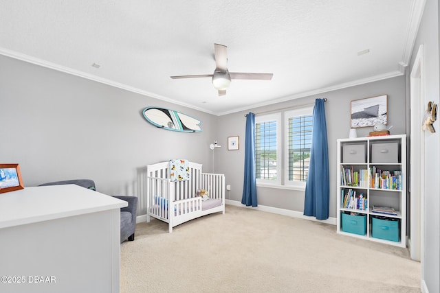 bedroom featuring a crib, crown molding, baseboards, and carpet flooring