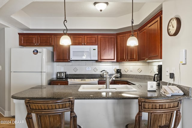 200 Ocean Crest Dr Unit 705, Palm Coast, FL 32137 - kitchen featuring white appliances, a peninsula, a kitchen bar, decorative light fixtures, and backsplash