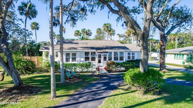 ranch-style house featuring driveway, entry steps, fence, and a front yard