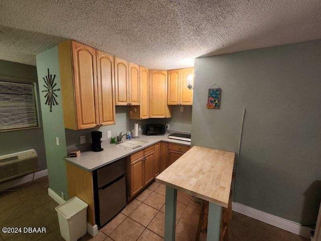 kitchen featuring light countertops, a sink, a textured ceiling, and light brown cabinetry