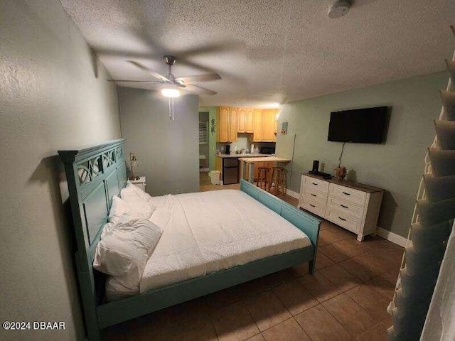 bedroom featuring a ceiling fan, dark tile patterned flooring, a textured ceiling, and baseboards