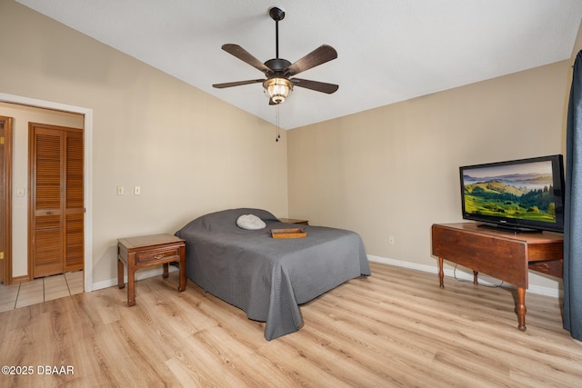 bedroom featuring light wood-type flooring, baseboards, vaulted ceiling, and a ceiling fan