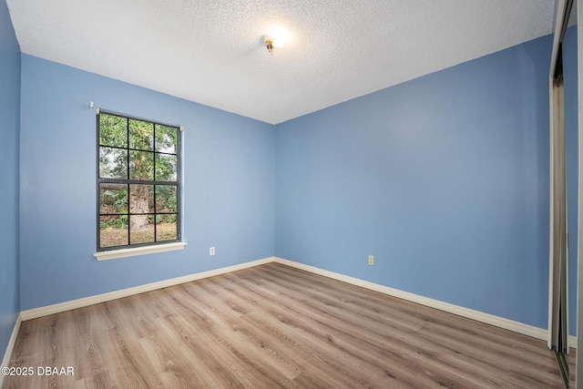 spare room featuring a textured ceiling, wood finished floors, and baseboards