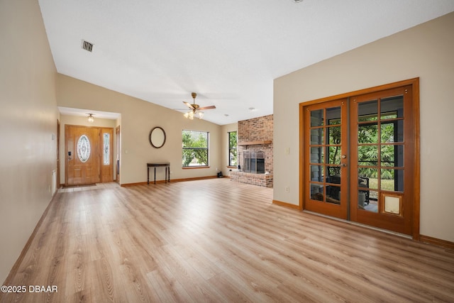 unfurnished living room featuring light wood-style flooring, visible vents, a ceiling fan, vaulted ceiling, and a brick fireplace