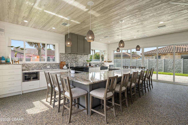 kitchen with visible vents, wooden ceiling, white cabinetry, and light stone countertops