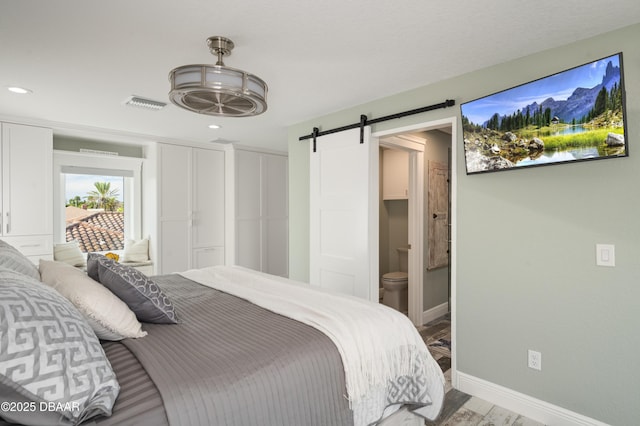 bedroom with a barn door, visible vents, baseboards, connected bathroom, and recessed lighting