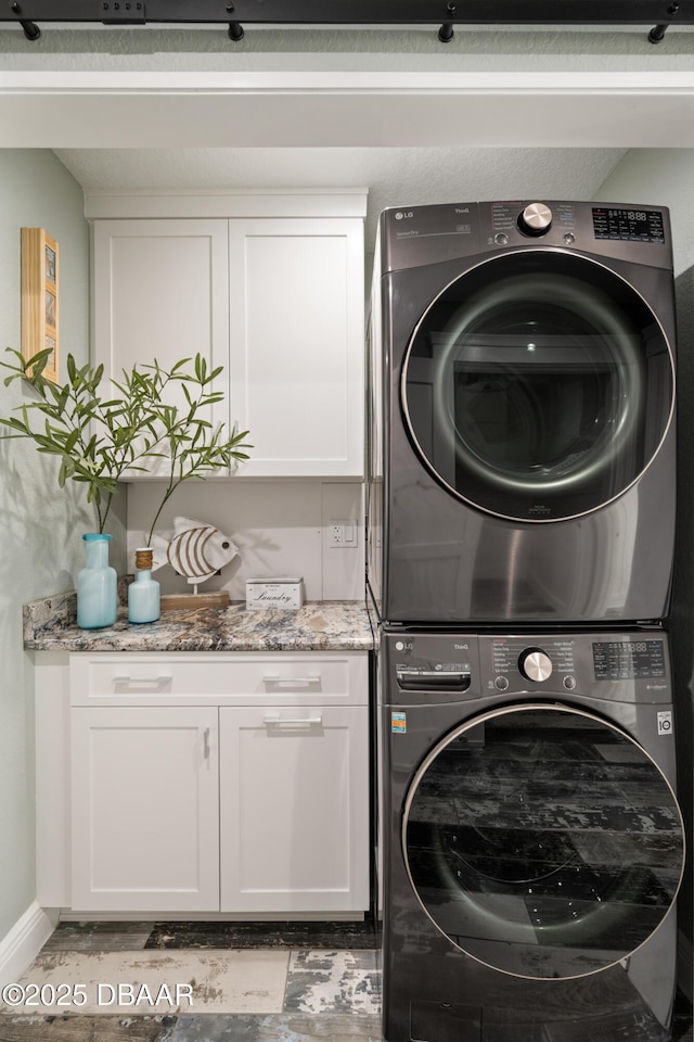 laundry room featuring stacked washing maching and dryer and cabinet space