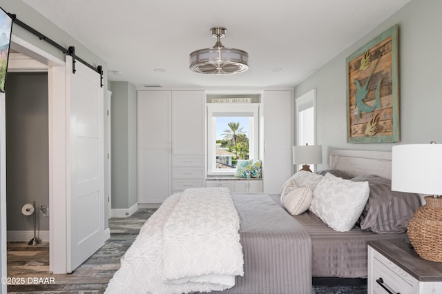 bedroom featuring a barn door, baseboards, and dark wood finished floors