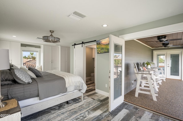 bedroom featuring a barn door, multiple windows, visible vents, and french doors