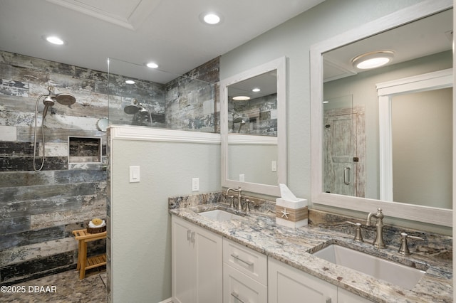 bathroom with recessed lighting, tiled shower, a sink, and double vanity