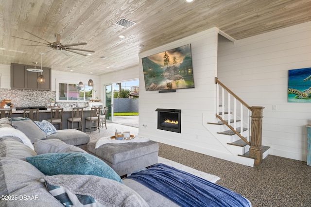 living room with a warm lit fireplace, visible vents, wooden ceiling, stairway, and recessed lighting