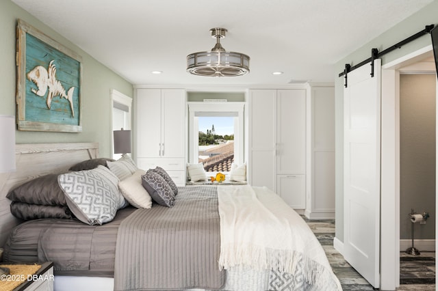 bedroom featuring baseboards, a barn door, wood finished floors, and recessed lighting